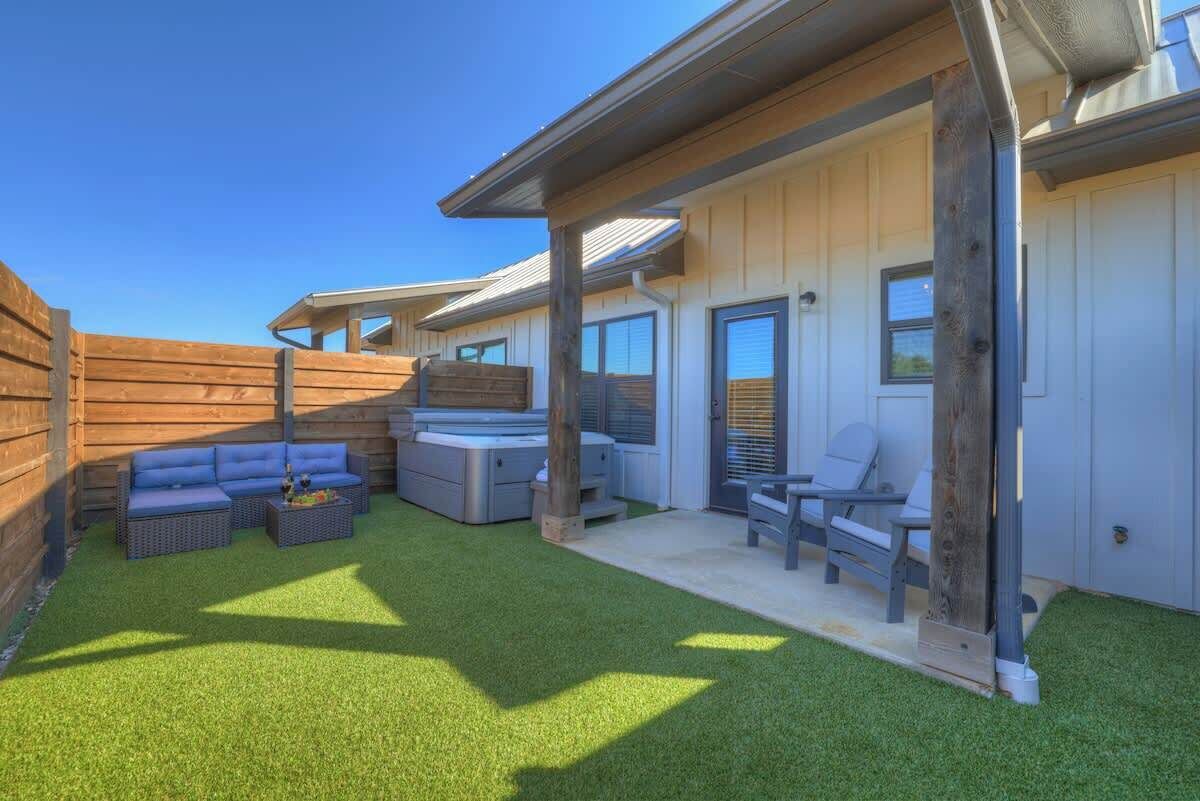 A modern outdoor patio area with a wooden deck, a blue sofa, a gray sofa, and a small table.