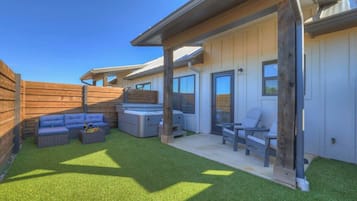 A modern outdoor patio area with a wooden deck, a blue sofa, a gray sofa, and a small table.