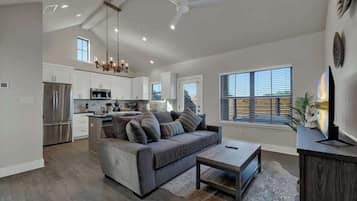 A spacious living area with a gray sofa, a coffee table, and a ceiling fan.