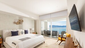 A hotel room with a large bed, a balcony with seating, and a TV mounted on the wall. - Harbor NT2307 by Moikkarentals (Puerto Vallarta)