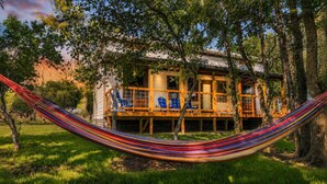 Un hamac dans un espace herbeux, avec un bâtiment en arrière-plan.