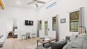 Un salon moderne avec un canapé, une table basse, un téléviseur et un ventilateur de plafond.