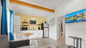A modern living room with a grey sofa, a wooden coffee table, and a TV mounted on the wall.