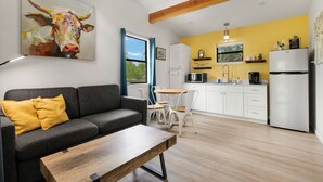 A modern living room with a grey sofa, a wooden coffee table, and a colorful cow painting on the wall.