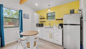 A compact kitchen with white cabinets, a microwave, a sink, and a refrigerator.