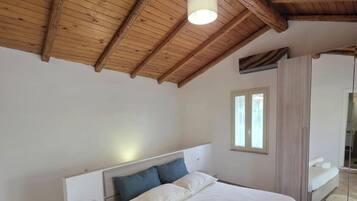A bedroom with a wooden ceiling, a bed with white linens, a nightstand, and a mirror.
