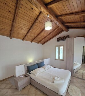 A bedroom with a wooden ceiling, a bed with white linens, a nightstand, and a mirror. - ALETNA HOME vacation home (Ragalna)