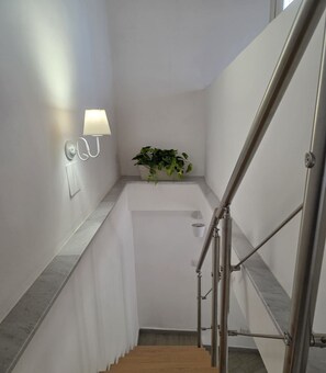 A modern staircase with a metal handrail, a wall-mounted light fixture, and a potted plant. - ALETNA HOME vacation home (Ragalna)