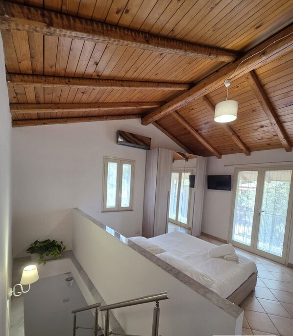 A bedroom with a wooden ceiling, a bed, a window, and a balcony. - ALETNA HOME vacation home (Ragalna)