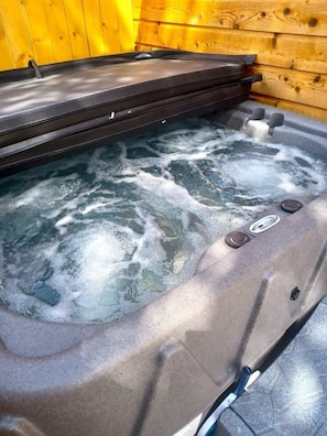A hot tub with a wooden wall backdrop.