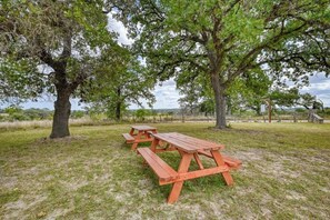 Ein Picknickbereich mit Holzbänken und Picknicktischen, umgeben von Bäumen und einer Wiese.