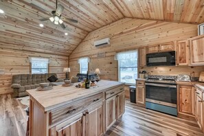 Interior de una cabaña de madera con cocina, comedor y sofá.