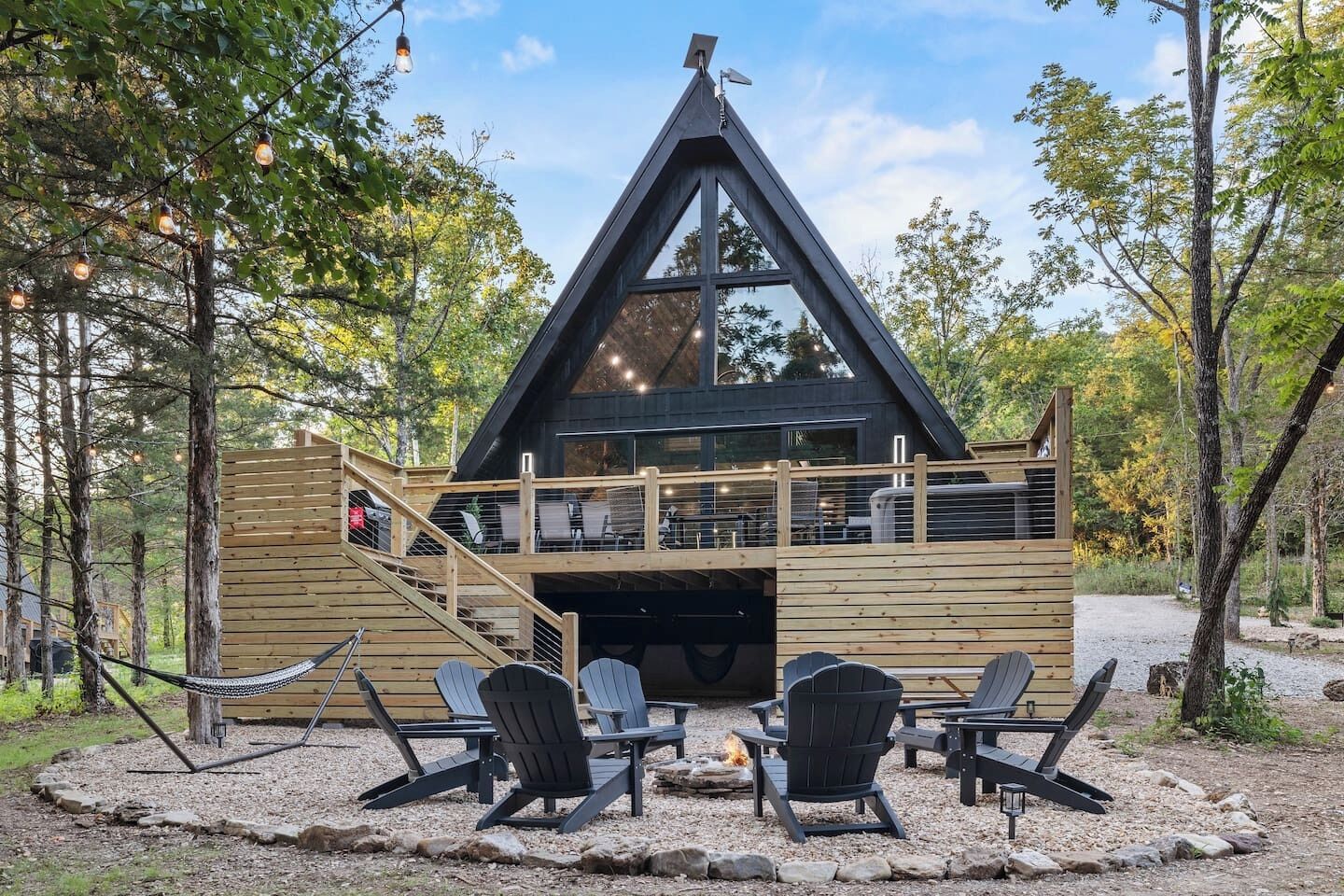 Eine Holzhütte mit einer Holzterrasse, Sitzgelegenheiten im Freien und einer Feuerstelle.