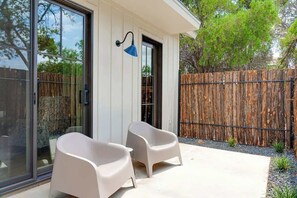 A modern outdoor patio with two white chairs and a blue wall-mounted lamp.