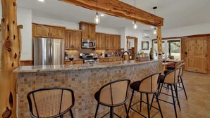 A kitchen with wooden cabinets, a central island with bar stools, and pendant lighting.