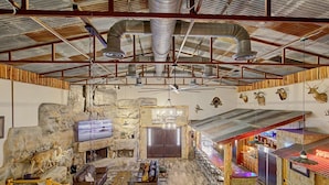 A rustic interior with stone walls, a fireplace, wooden furniture, and mounted animal heads.