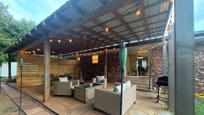 Un'area patio esterna con pavimento in pietra, mobili in vimini e luci a catena.