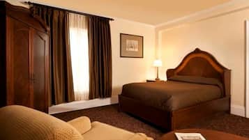 A hotel room with a bed, a chair, a lamp, and a framed picture on the wall.