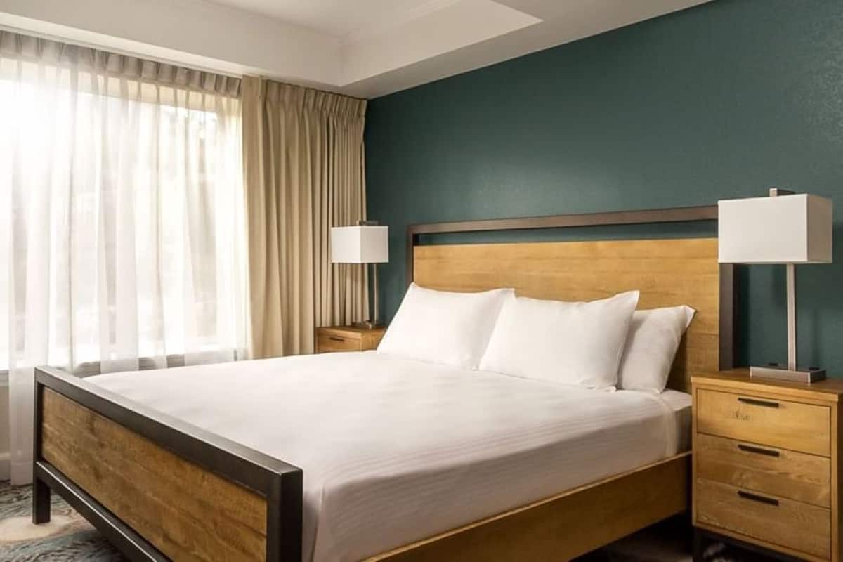 A hotel room with a bed, two bedside tables, a lamp, and a window with curtains.