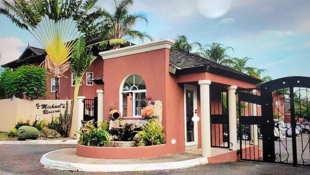 A building with a red facade, a gated entrance, and a sign reading "Michael's Rivera".