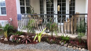 A covered outdoor seating area with wicker furniture and potted plants.