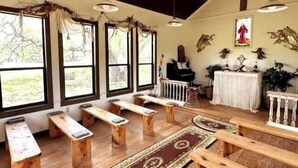 Interior de iglesia con bancos de madera, un piano y decoraciones religiosas.