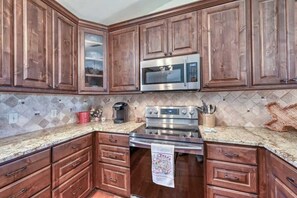 A kitchen with wooden cabinets, a stainless steel microwave, and a stove.