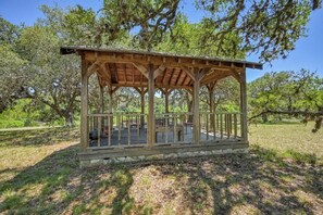 Un belvédère en bois doté d’une terrasse couverte, entouré d’arbres.