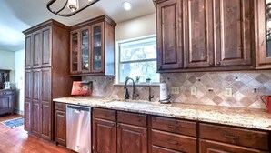 Una cocina con gabinetes de madera, lavavajillas de acero inoxidable y encimera de granito.