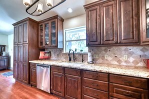 A kitchen with wooden cabinets, a stainless steel dishwasher, and a granite countertop.
