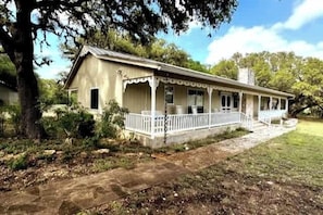 A single-story house with a porch, surrounded by trees and a grassy yard. - 45-ac Estate-Private Blanco River Access-Fire Pit! (Blanco)