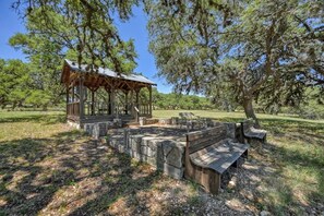A wooden gazebo with a bench and stone seating area in a park.