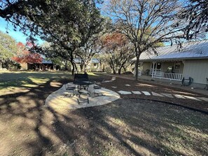 Un parc avec une table de pique-nique, des arbres et un bâtiment doté d’une véranda.