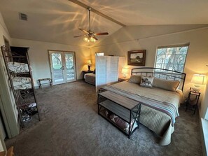 Une chambre à coucher avec un lit, un ventilateur de plafond, une armoire, un banc et une fenêtre.