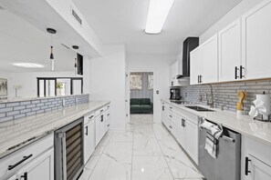 Une cuisine moderne avec des meubles blancs, un plan de travail en marbre et un îlot central.