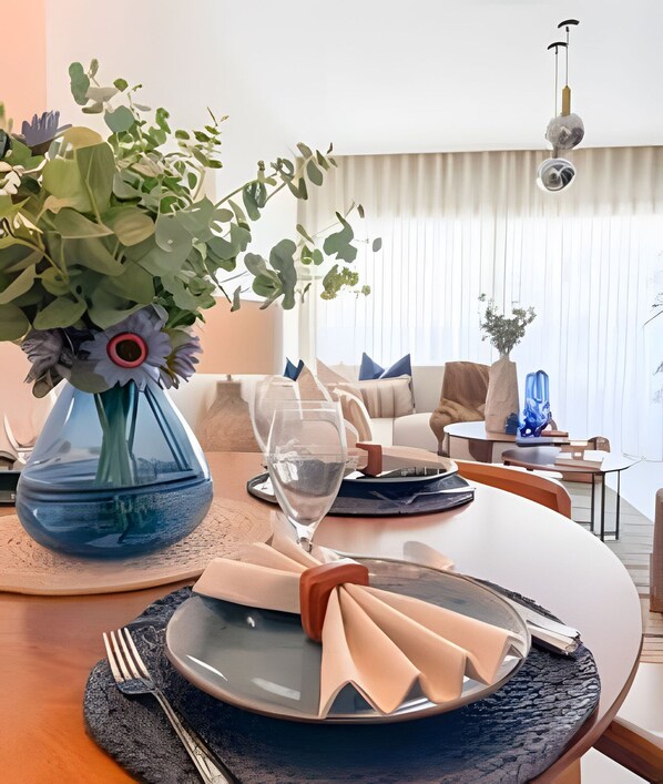 A dining table set with plates, a vase of flowers, and a clear glass.