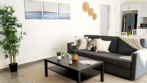 Un salon moderne avec un canapé noir, une table basse et une plante en pot.