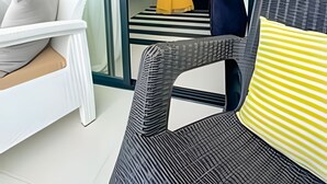 A modern living room with a glass door leading to a balcony, a dining area with a black and white striped rug, and a kitchen visible through the glass. - Condo in Epic Punta Cana! Near Cocobongo (Punta Cana)