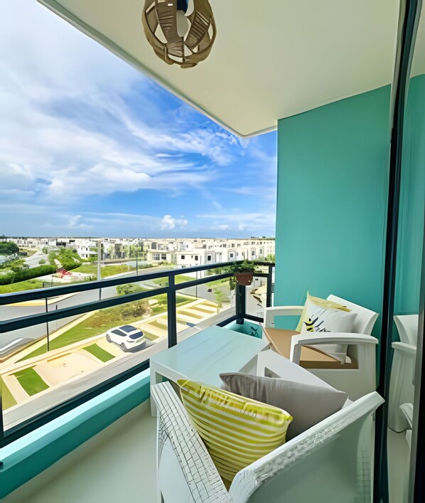 A balcony with a view of a residential area, a white sofa with cushions, and a hanging light fixture.