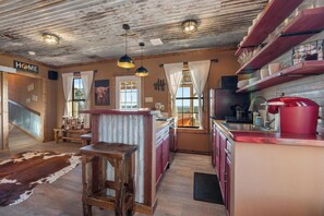 A rustic kitchen with wooden cabinets, a red sink, and a cowhide rug.