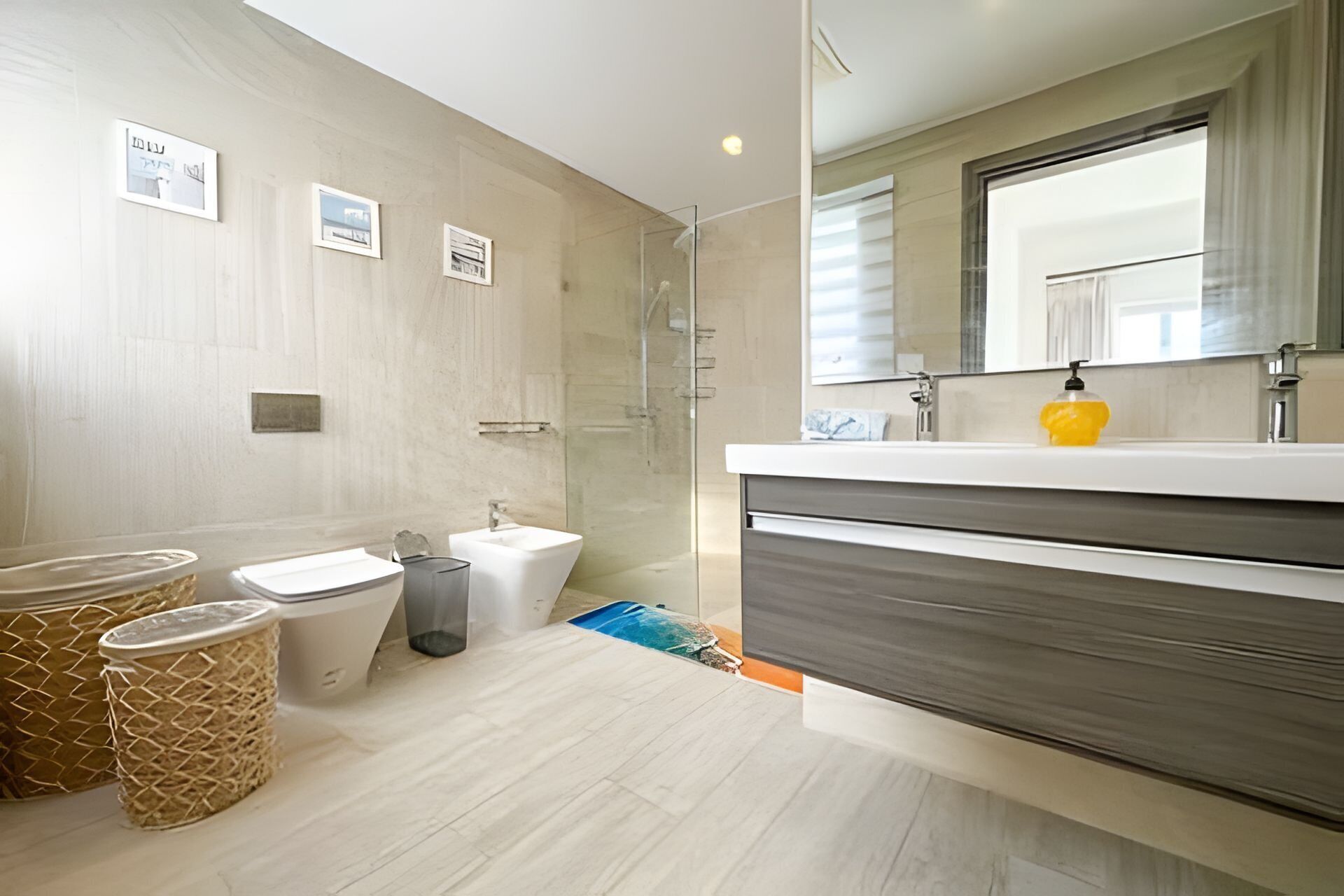 A modern bathroom with a shower, two sinks, a large mirror, and a yellow soap dispenser.