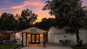 A house with a 'HOME' sign, a covered porch, a garage, and a patio with chairs.