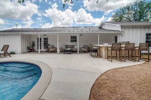 A covered patio area with a pool, outdoor seating, and a barbecue grill.