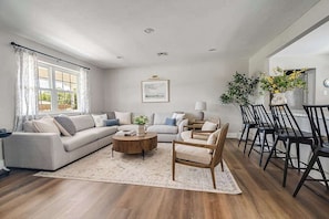 Un salon comprenant un canapé, des fauteuils, une table basse et un coin repas avec des chaises.