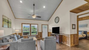 Amplia sala de estar con un conjunto de sofás, un televisor y una pared decorativa de madera.