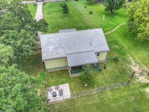 A two-story house with a green roof and a fenced backyard.