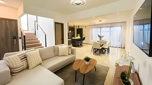 A modern living room with a sofa, coffee table, and a dining area with a table and chairs. - Family Villa in Punta Cana! Heated Pool (Punta Cana)