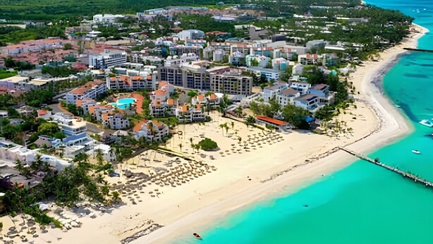 An aerial view of a coastal resort area with a beach, buildings, and a pier. - Incredible Studio in the heart of Punta Cana (Punta Cana)