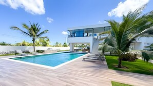 A modern house with a swimming pool, a covered patio, and a well-maintained lawn. - Incredible Studio in the heart of Punta Cana (Punta Cana)
