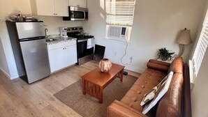 A modern kitchen with a refrigerator, stove, microwave, and oven. There is a wooden table with a vase and a brown leather sofa. - Cozy cabin in nice Wylie with AC (Wylie)